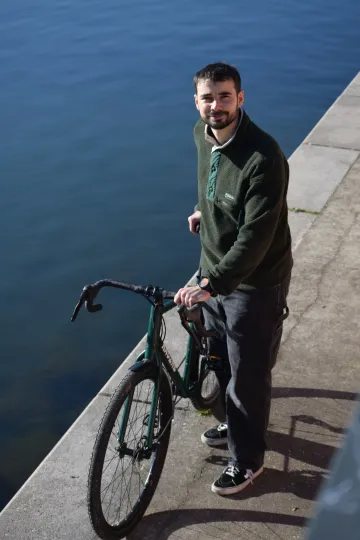 Victor DEWEERDT avec le vélo Vélos-Racine vert mousse au bord de l'Ill à Strasbourg